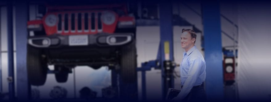 A man wears a suit in a car workshop