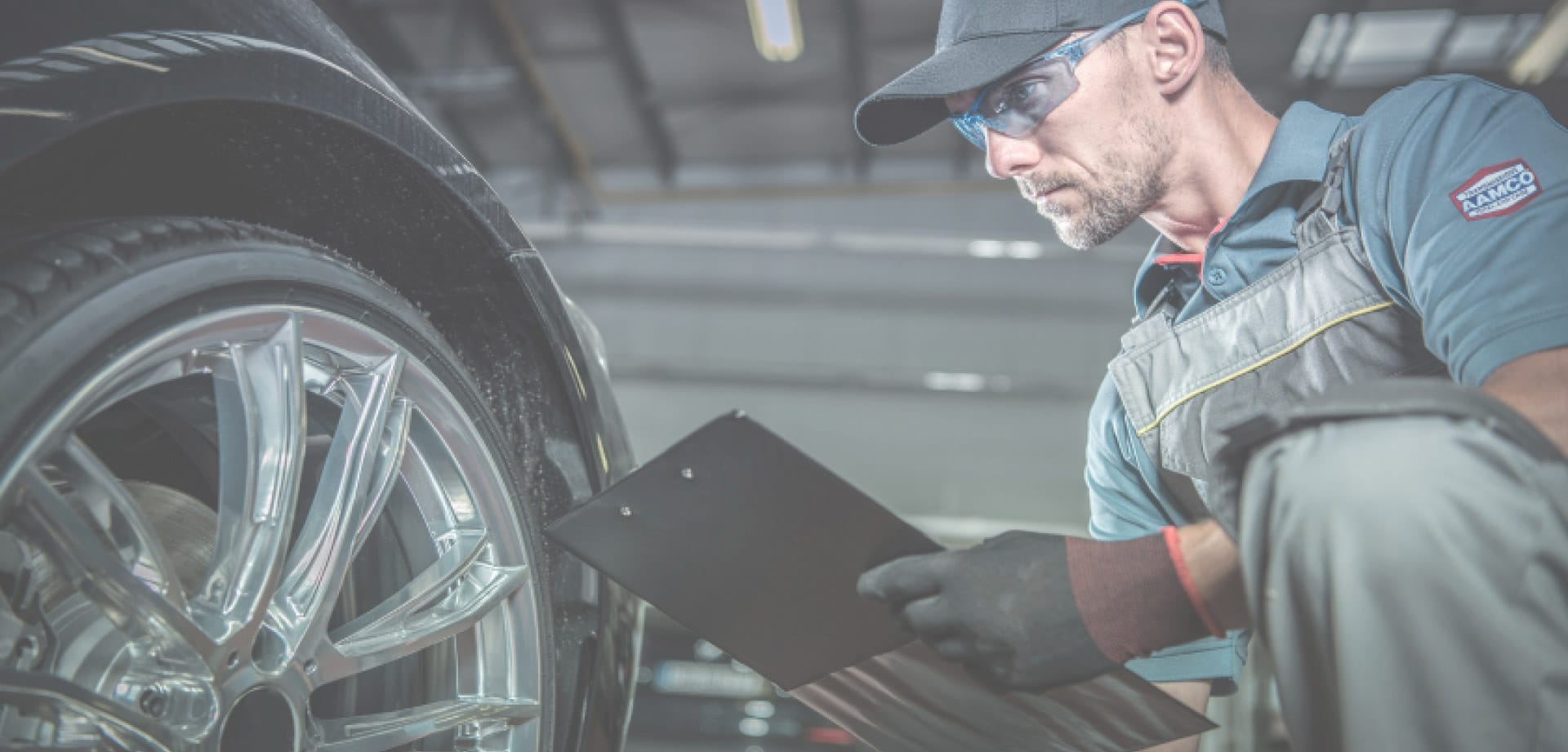 A man wearing protective glasses analyses a car wheel