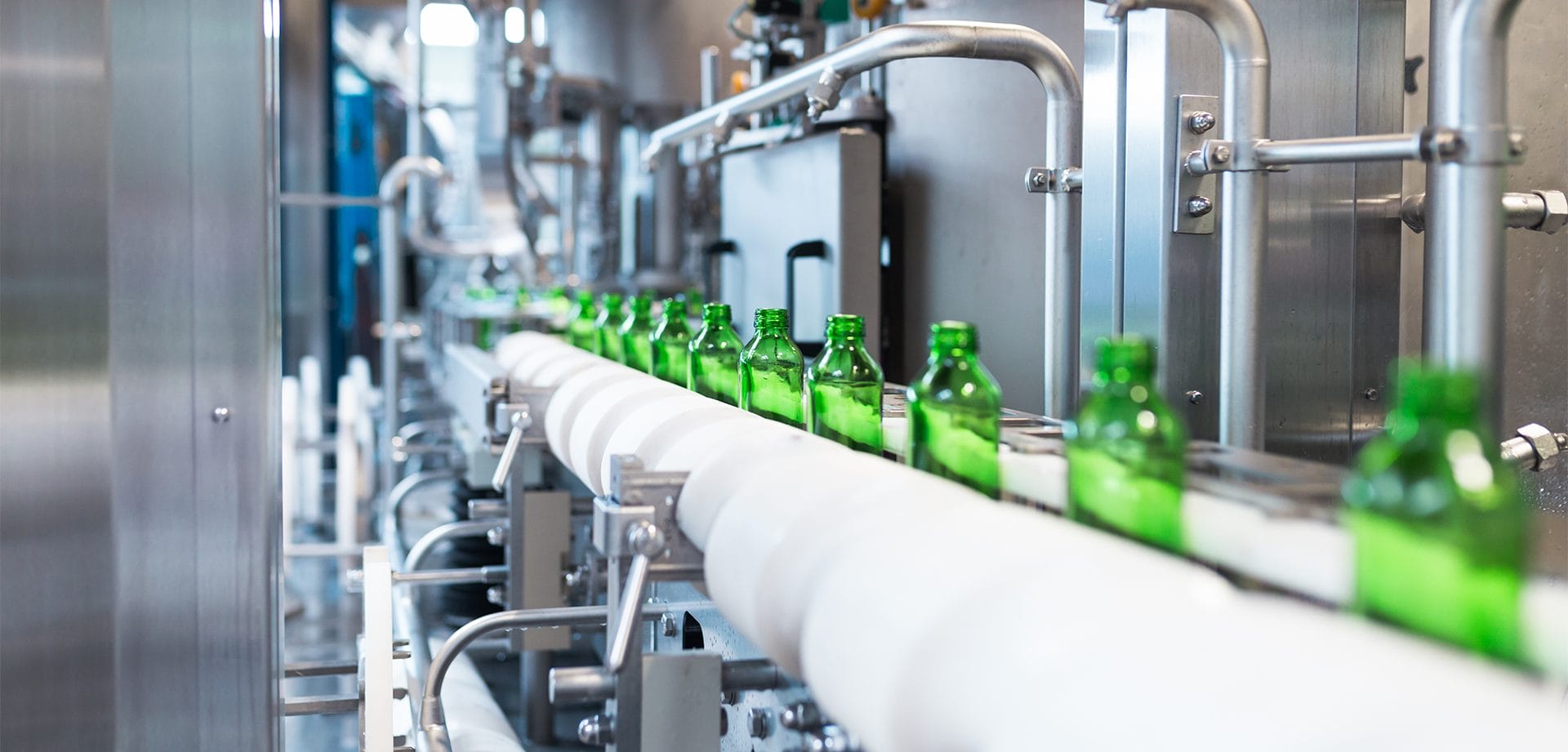 Green bottles are lined on a conveyer belt