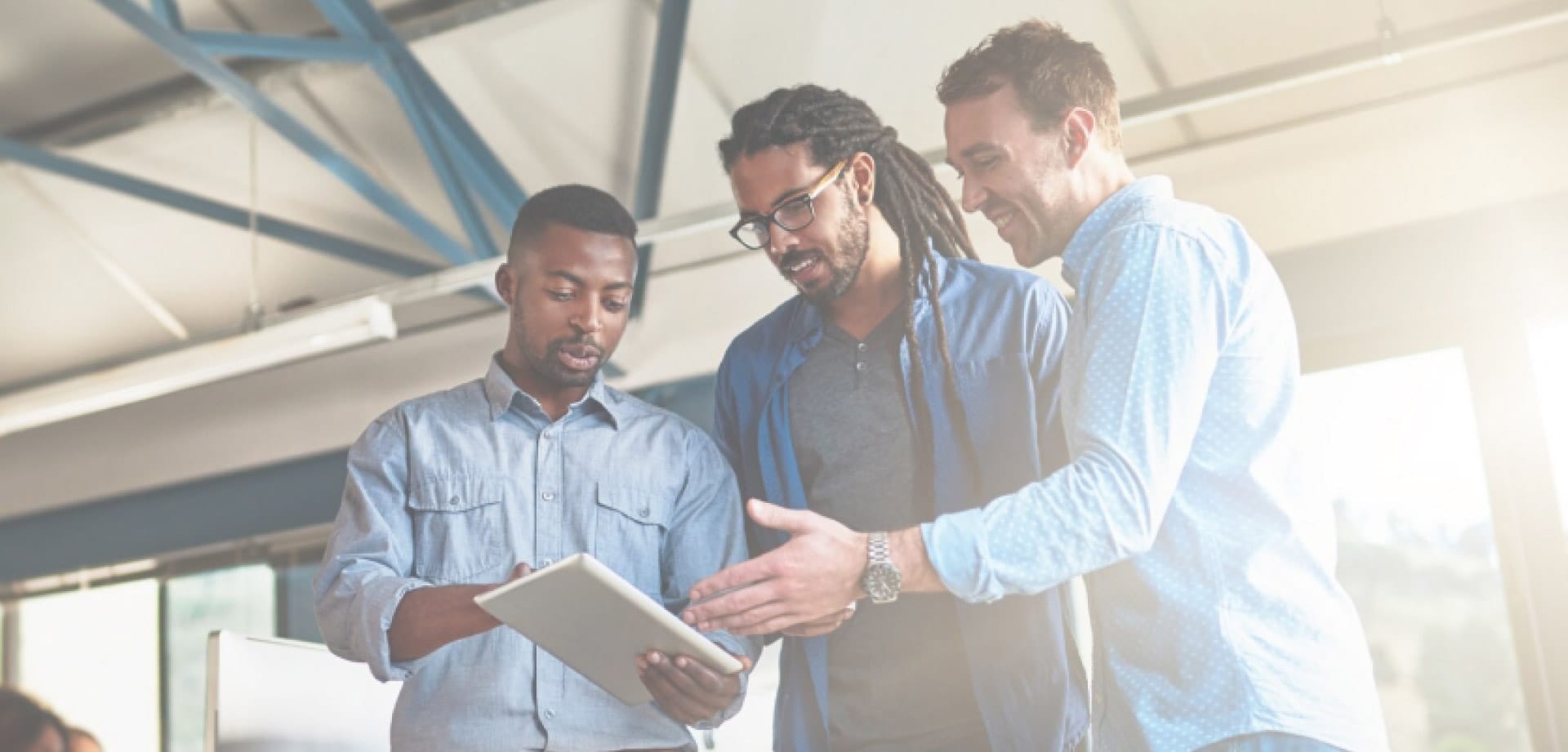 Three men look at a notebook together
