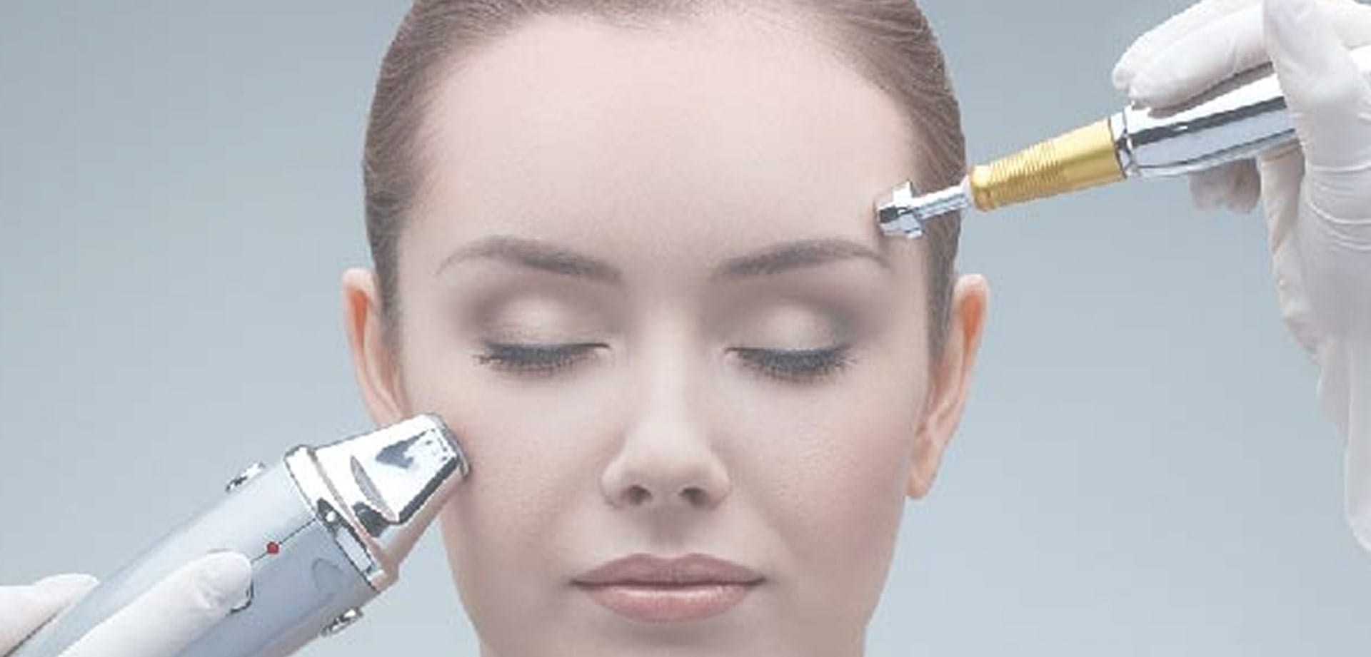 Close-up of a person receiving a facial treatment with handheld skincare devices near the forehead and cheek