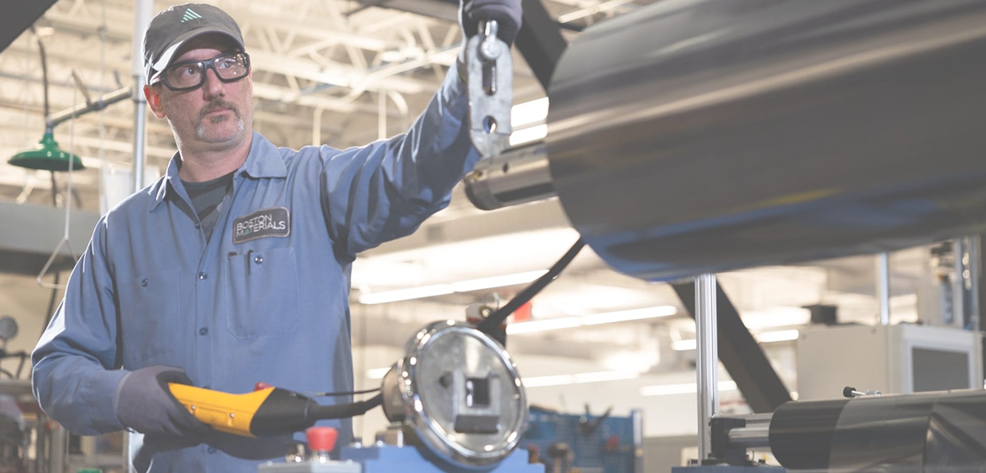 Background image for Boston Materials' case study showing an employee working with industrial equipment in a manufacturing facility
