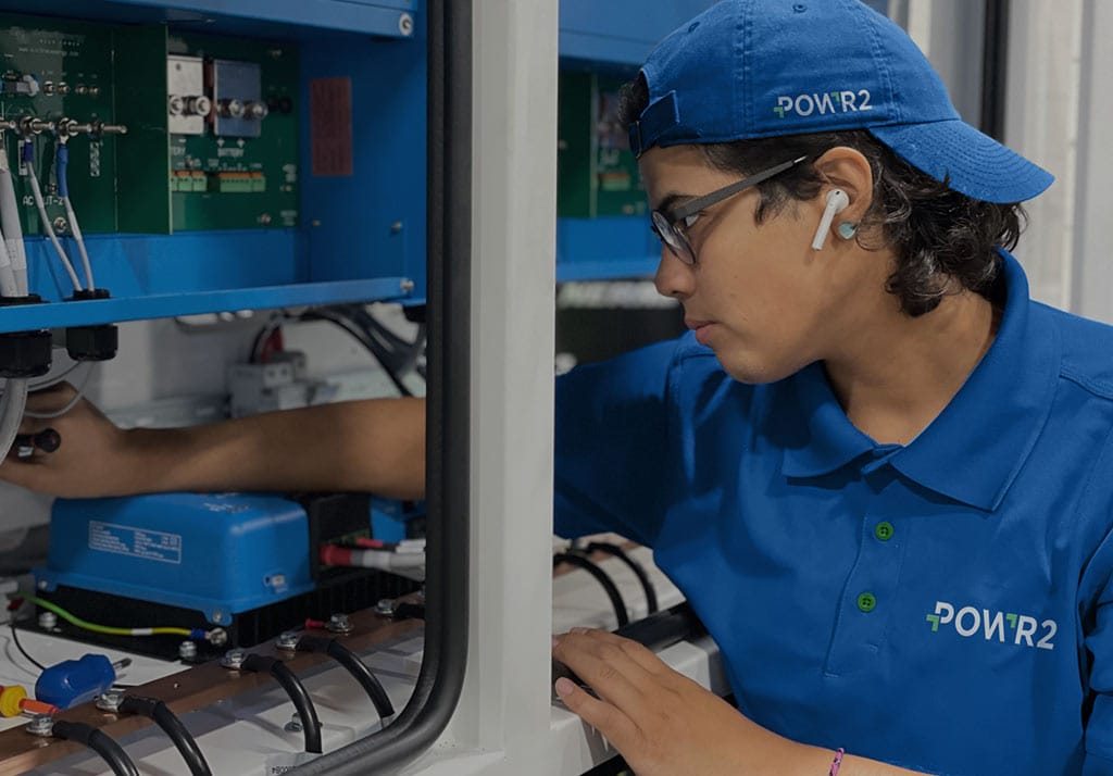Manufacturing technician inspecting electrical equipment inside an industrial control cabinet.
