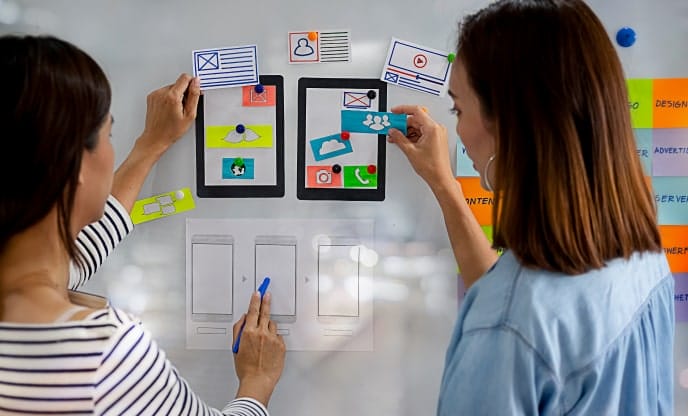 SEO team planning website layout and content on a whiteboard with wireframes, app screens, and sticky notes